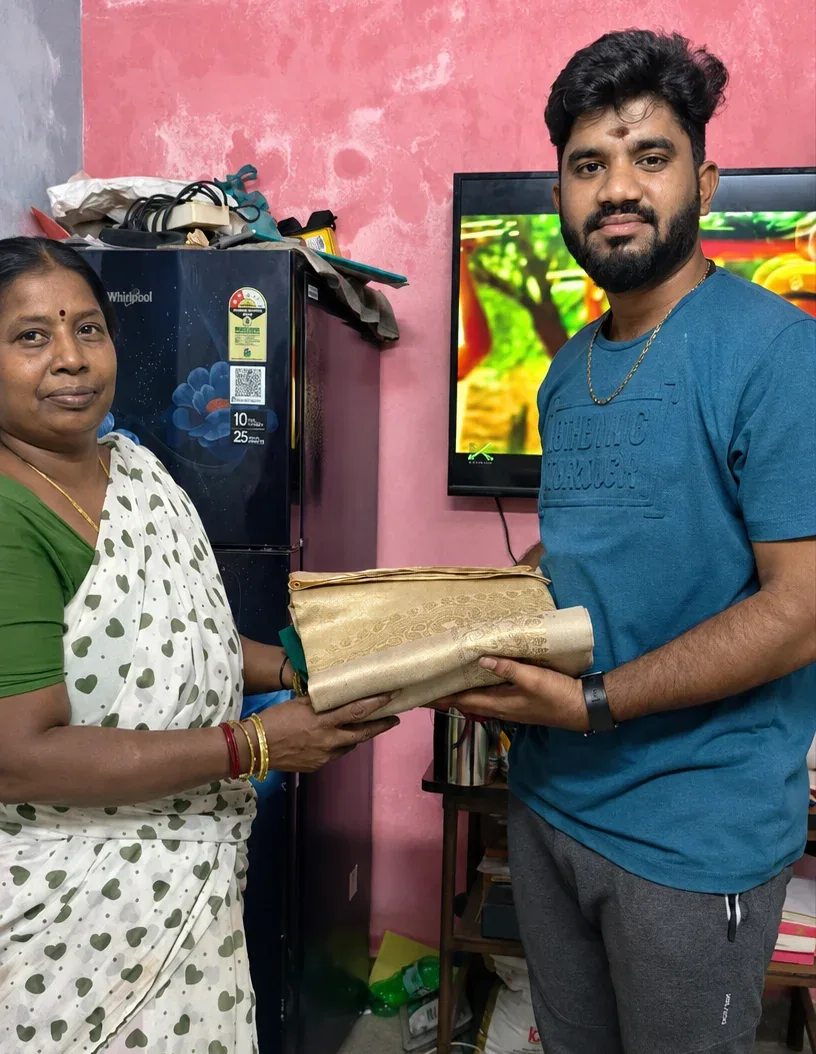 Customer handing over a golden silk saree to our team at home