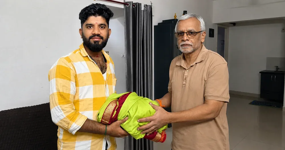 Customer handing over a green and maroon silk saree at home
