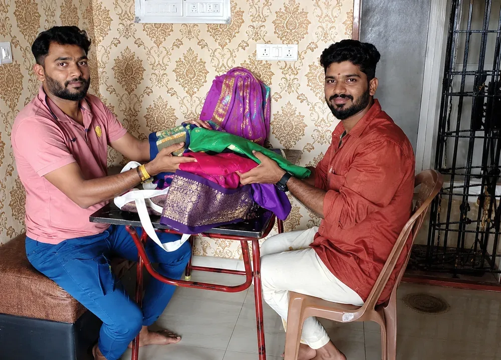 Our team reviewing colourful silk sarees with a customer