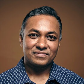 A studio portrait of a handsome Indian man.